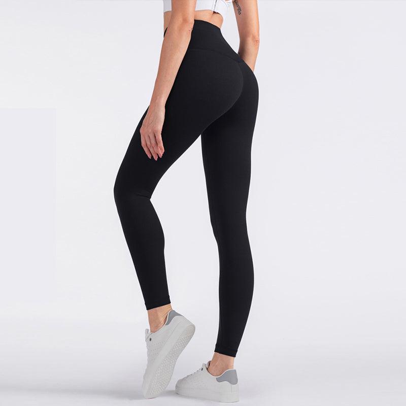 Woman wearing black high-waisted seamless yoga pants with tummy control and butt-lifting design, side view showing back waistband pocket.