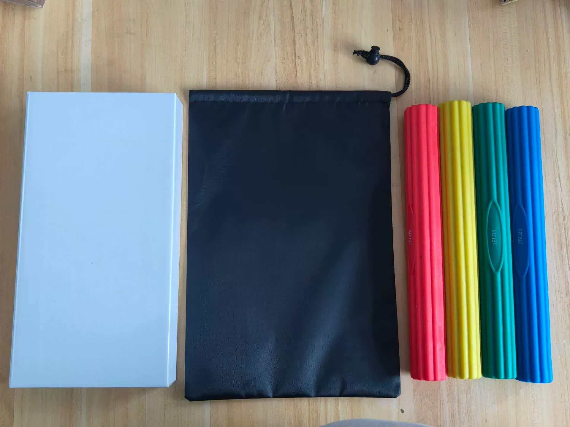 Multifunctional resistance bar set with four colorful silicone bars and a black storage bag on a wooden surface for fitness and muscle recovery.