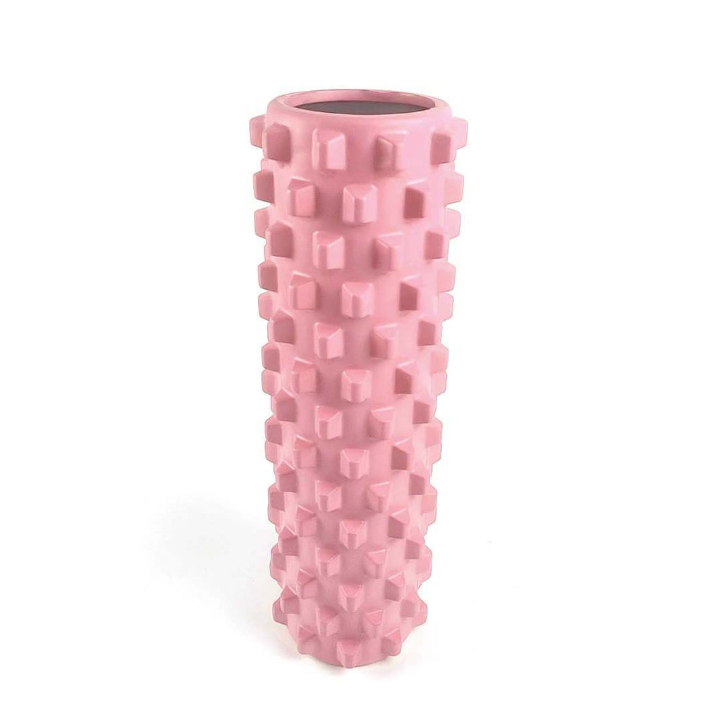 Pink solid yoga foam roller with textured wolf tooth design for muscle relaxation and massage.