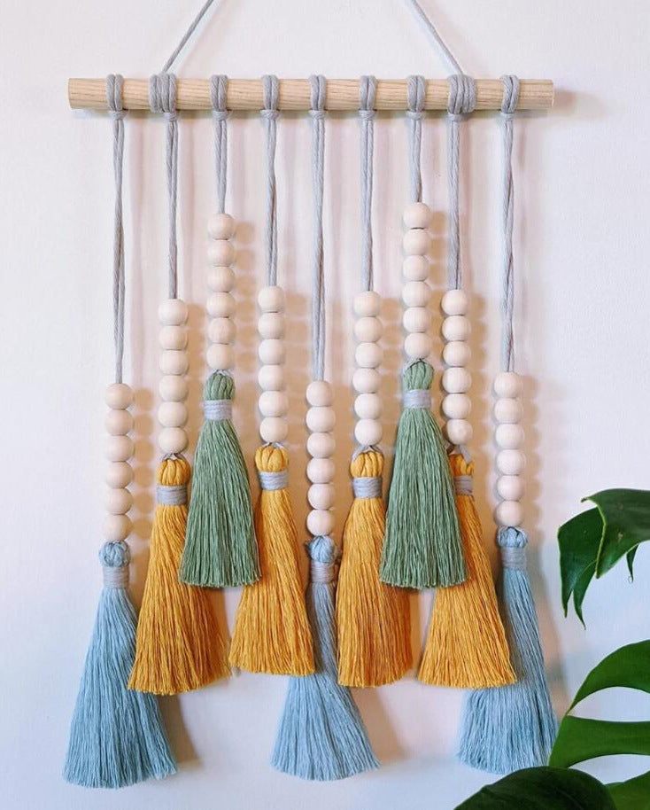 Colorful tassel wall hanging with wooden beads in light blue, green, and yellow, handmade boho macrame tapestry decor